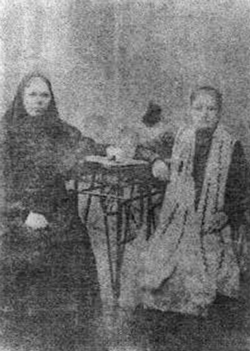 Слева сидит одна из монахинь, ведшая подвижническую жизнь в монастыре. Фото начала XX столетия.